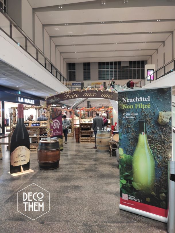 Foire aux vins Marin centre, bouteilles peintes, tonneaux, tables hautes, vignes, présentoirs, portique