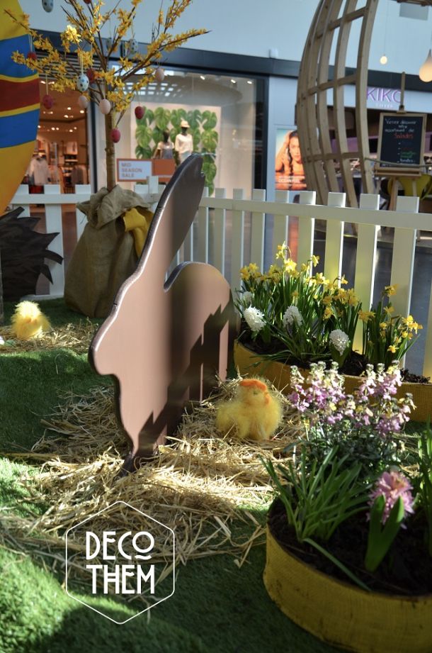 décoration fleurie de pâques, barrières blanches, bac avec des fleurs, lapin de pâques, lapin en chocolat, poussins, gazon