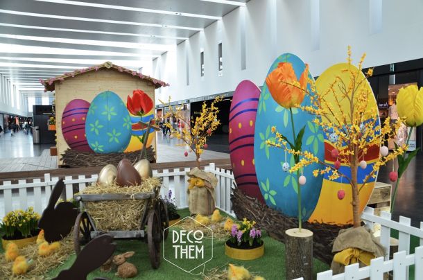 Décoration pâques, barrières blanche, tulipes géantes, gazon, parterre fleuri, charrettes avec des gros œufs, forsythia en fleurs, œufs de pâques géants, poussins , paille, chalet en bois